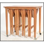 A 1970's retro teak wood quartetto nest of tables raised on turned legs with a series of tables to