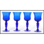 A set of four unsigned Bristol Blue glass goblet wine glasses raised on circular bases with baluster