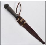 A South African tribal dagger having a leather sheath with a belt loop, and a turned wooden handle.