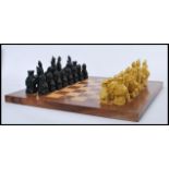 A 20th Century chess set made of contrasting stained wood, having Chinese resin figures with foo dog