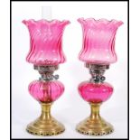 A pair of 19th Century Victorian oil lamps having cranberry glass shades with fanned rims and