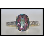 A stamped 375 9ct gold ring set with an oval cut purple and green iridescent stone and white