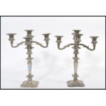 A matching set of three silver plated candelabras raised on square bases with scrolled arms and