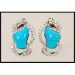 A pair of silver stud earrings set with turquoise stones and cubic zirconia.