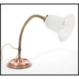 A vintage retro 20th century industrial copper gooseneck desk lamp raised on a circular base with