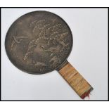 A 19th century Japanese bronze hand mirror having cane wrapped handle. The central circular mirror