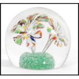 A 20th century domed spherical form glass paperweight with three flowers on a green ground to the