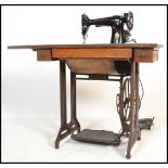 An early 20th century Singer treadle sewing machine table having a cast and wrought iron pedestal