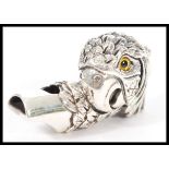 A stamped sterling silver whistle in the form of a parrot having yellow and black glass eyes and a