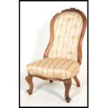 A Victorian 19th century walnut spoonback nursing chair being raised on cabriole type legs with hoof