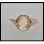 A stamped 9ct gold cameo ring set with an oval cameo head facing right with decorative shoulders.