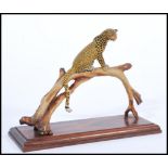 A 20th century cold painted bronze figurine of a leopard on perched on bronze tree mounted on plinth