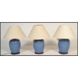 A set of 3 contemporary large ceramic blue glaze bulbous table lamps - lights. Each raised on wooden