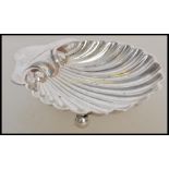 An early 20th century silver hallmarked scallop dish raised on bun feet with shaped handle.