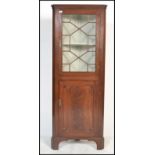 A Georgian 19th century mahogany corner cupboard of thin proportions having astragal glazed