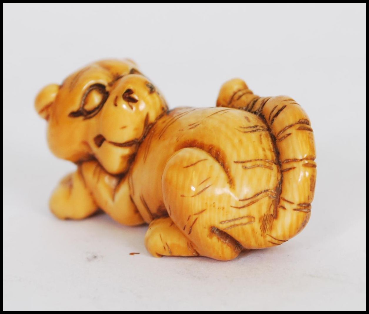 A rare Meiji period ivory Netsuke of a crouching tiger, its head turned back with long striped - Image 9 of 10