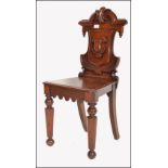 A Victorian 19th century solid mahogany armorial hall chair. The unusual shaped back with a