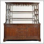 An 18th century oak dresser. Raised on stile supports, the wide body comprising a series of