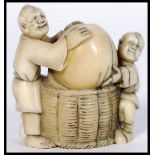 An unusual Japanese Meiji period carved ivory netsuke depicting two actors holding a large nut set