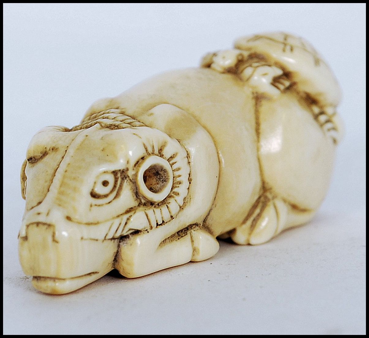 A rare and unusual 19th century Meiji period ivory Netsuke of a crouching / seated ox with
