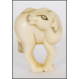 A rare Meiji period ivory Netsuke of a Bactrian camel. The head of the camel turned back standing on