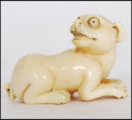 A rare Meiji period ivory Netsuke of a crouching dog with its head turned back, sat on 4 feet,