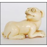 A rare Meiji period ivory Netsuke of a crouching dog with its head turned back, sat on 4 feet,