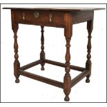 A 17th century country oak lowboy / writing table desk. Raised on block and turned legs united by