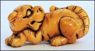 A rare Meiji period ivory Netsuke of a crouching tiger, its head turned back with long striped