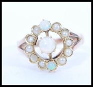 An early 20th Century 9ct gold ring set with a round opal with two smaller accent opals and a halo