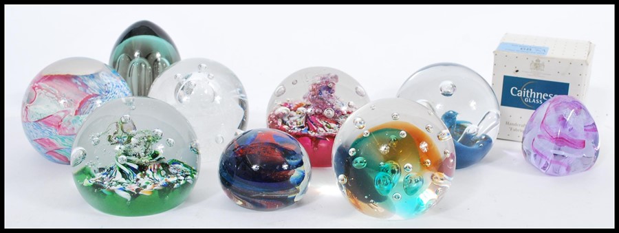 A collection of nine 20th century glass paperweights, the paperweights predominately by Caithness,