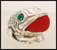 A stamped 925 silver pincushion in the form of a toad having faceted emerald eyes and a red fabric