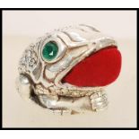 A stamped 925 silver pincushion in the form of a toad having faceted emerald eyes and a red fabric