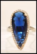 A stamped 925 silver ring set with a large pear shaped faceted blue stone with cz accent stones.