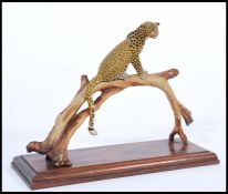 A 20th century cold painted bronze figurine of a leopard on perched on bronze tree mounted on plinth