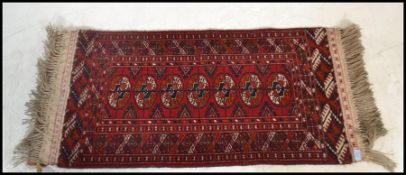 An early 20th century Islamic - Persian Bokhara rug with red ground having geometric borders,