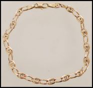 A 9ct gold decorative link bracelet having a curb link with floral spacers and a lobster clasp.