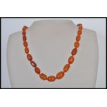 A vintage amber bead necklace having a yellow metal clasp with 31 hand knotted graduating amber