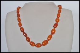 A vintage amber bead necklace having a yellow metal clasp with 31 hand knotted graduating amber