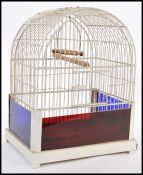 A vintage 20th Century bird cage having white bars and a wooden perch to the interior with blue