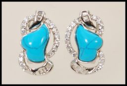 A pair of silver stud earrings set with turquoise stones and cubic zirconia.