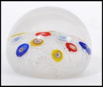 A 20th Century glass paperweight with random murrine canes atop a muslin ground cased in a clear