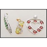 Three white and yellow 9ct gold pendants to include a white gold heart shaped with red stones, a