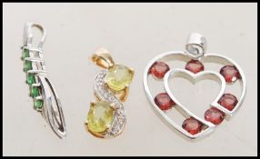 Three white and yellow 9ct gold pendants to include a white gold heart shaped with red stones, a