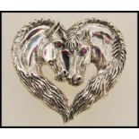 A sterling silver brooch in the form of two horses set with rubies for eyes. Weight approx 19.0g.