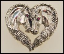 A sterling silver brooch in the form of two horses set with rubies for eyes. Weight approx 19.0g.