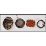 A collection of four 19th Century polished stone brooches set within silver white metal mounts.
