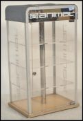 A shop display / counter top revolving illuminated display cabinet having shelves to the interior