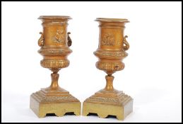 A pair of 19th century bronze urns raised on square bases with decorations of swags and ribbons with