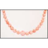 A vintage pink salmon coral bead necklace having a floral gilt clasp.